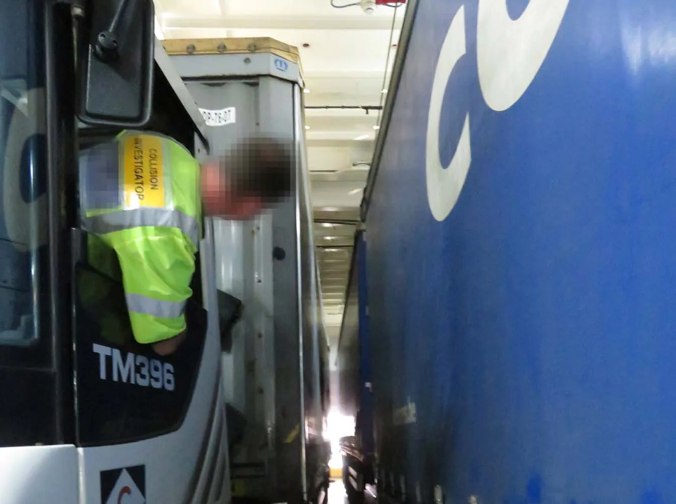 Reconstruction on a ro-ro vehicle deck, with a person leaning out of a tug cab to see along the narrow gap between two trailers